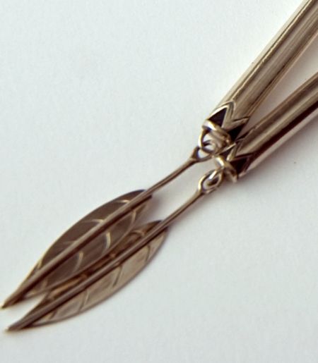 Close-up of silver bolo tie cord tips adorned with silver bangle tips resembling tree leaves